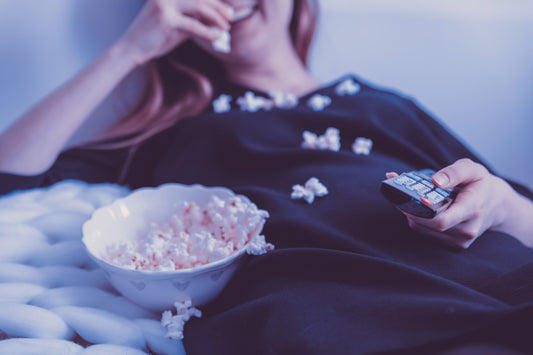 Photo of woman eating popcorn and watching TV by JESHOOTS.COM on Unsplash