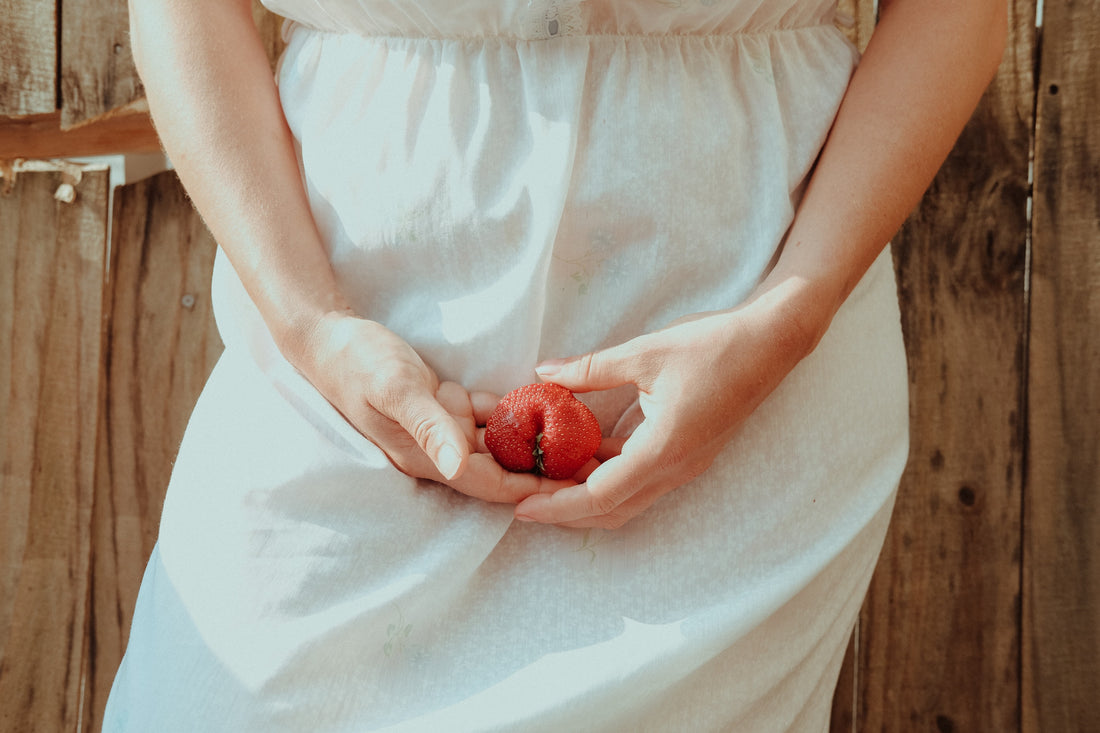 Woman holding a strawberry by her crotch by Timothy Meinberg on Unsplash
